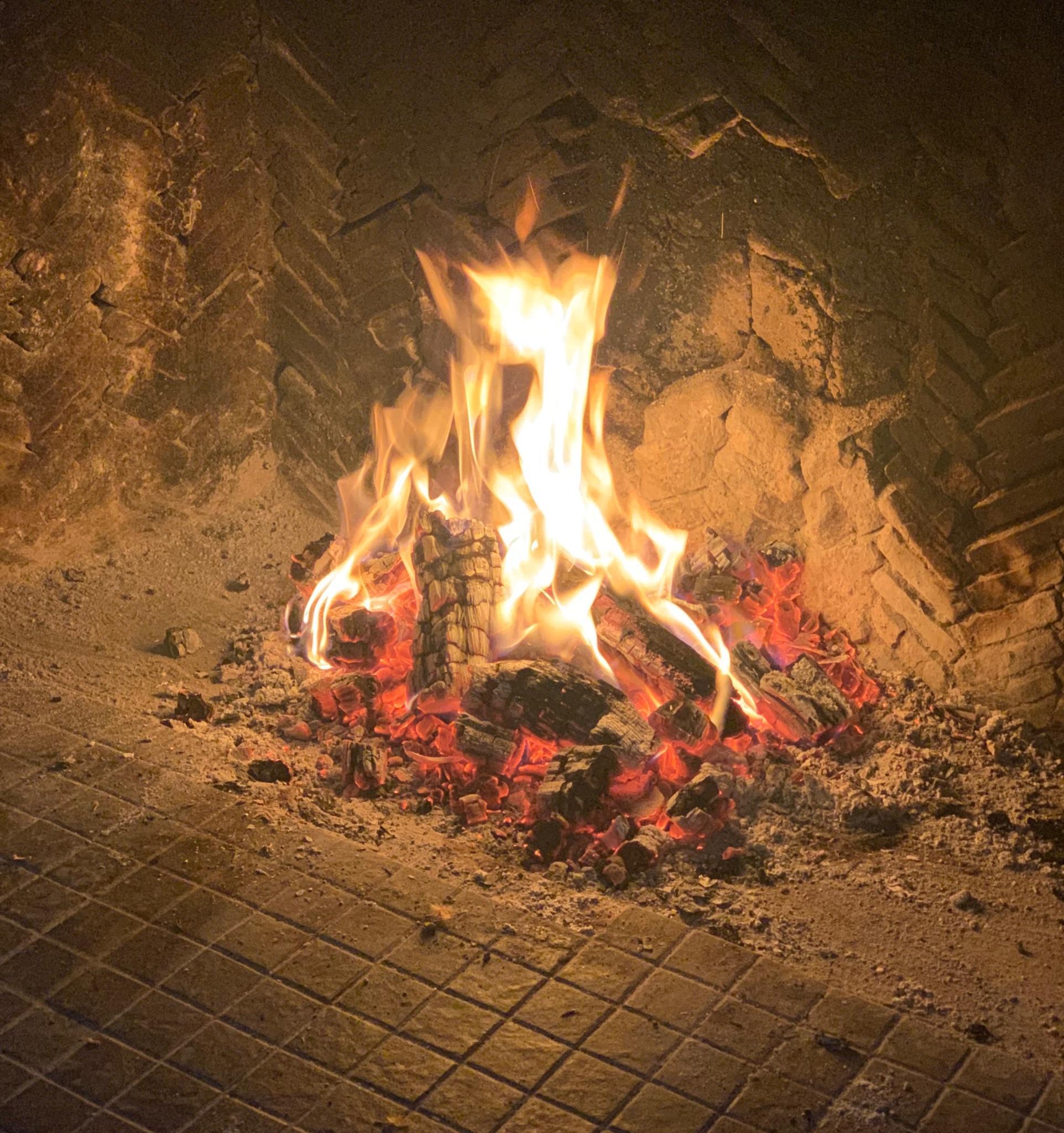 A fire burning down to glowing embers in a brick fireplace
